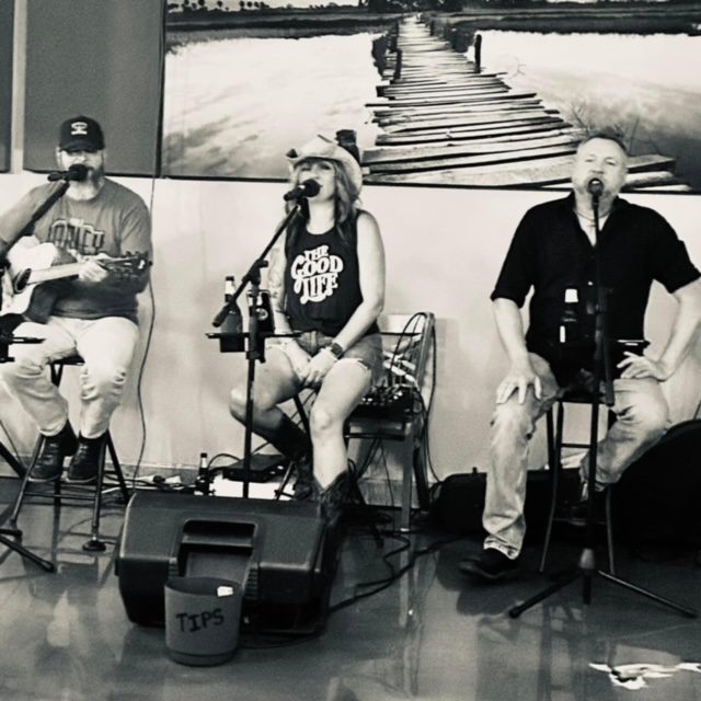 Three people sitting on stools with guitars