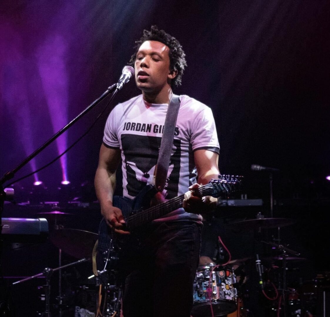 A man with a guitar in front of a microphone.