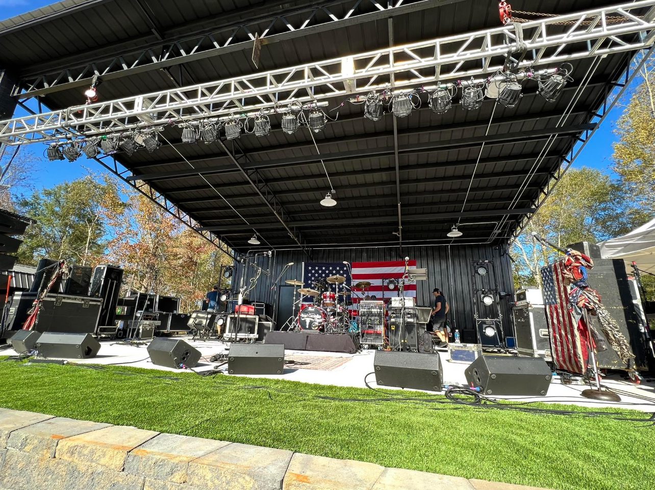 A stage with speakers and lights on the grass